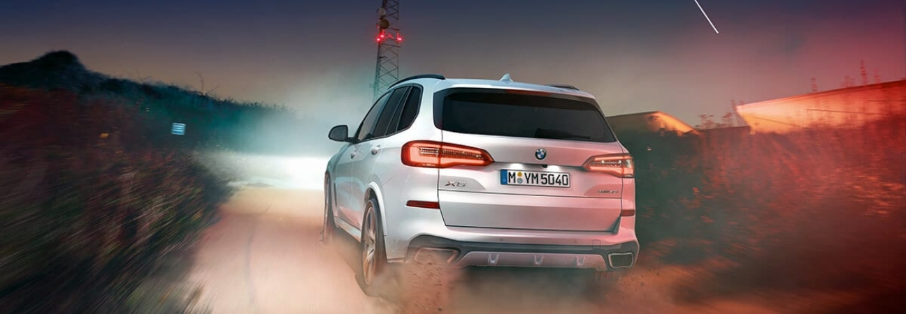 White 2019 BMW X5 driving down a desert road at dusk.
